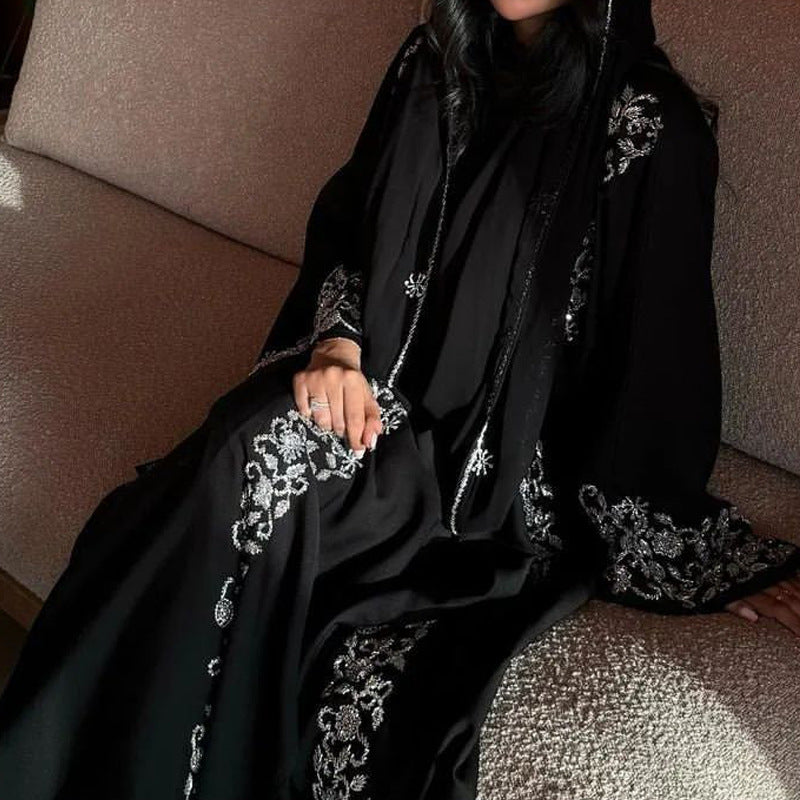 Person wearing a black embroidered abaya sitting on a couch.