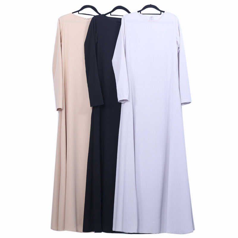 Three long-sleeve dresses in beige, black, and white on hangers against a white background.