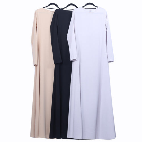 Three long-sleeve dresses in beige, black, and white on hangers against a white background.