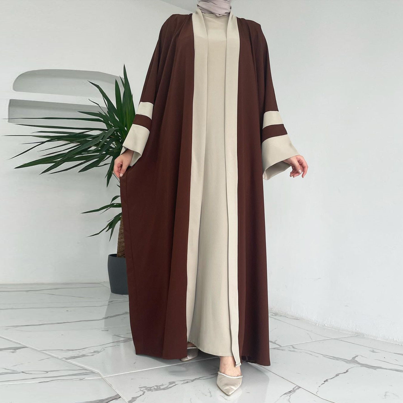 Woman wearing a brown and beige abaya with a white background