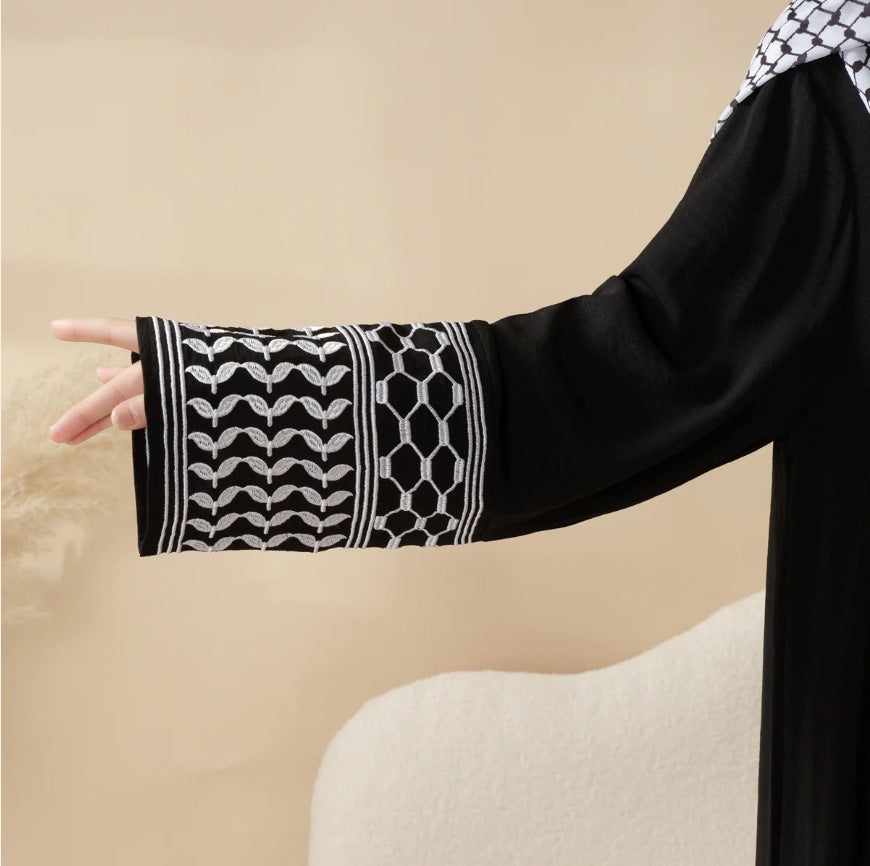 Black sleeve with white geometric pattern worn by a person against a beige background