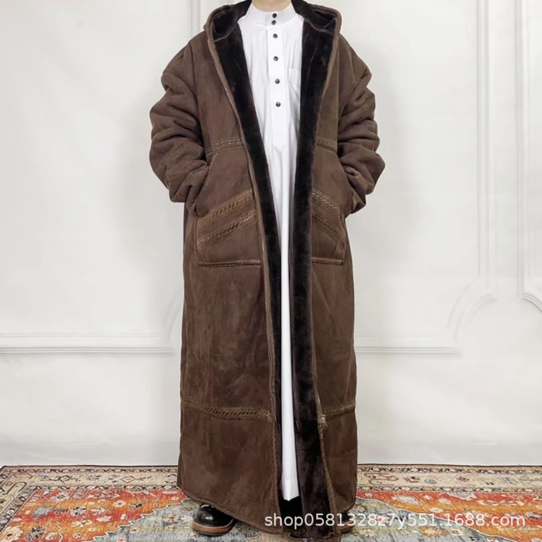 Brown long coat worn by a person against a white wall.