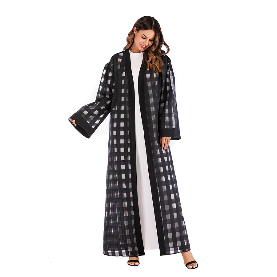 Woman wearing a long black and white checkered coat on a white background