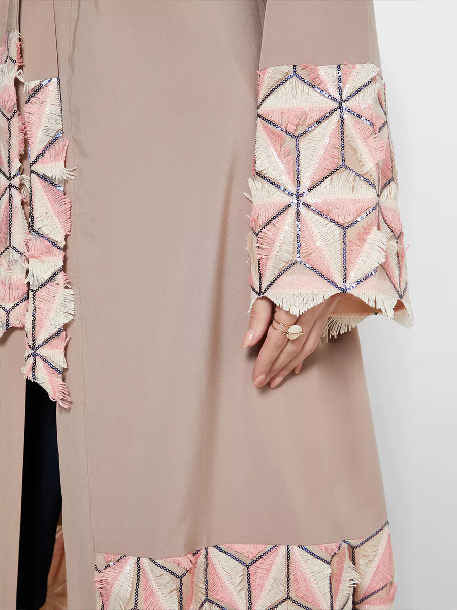 Close-up of a beige garment with a patterned pink and white trim.