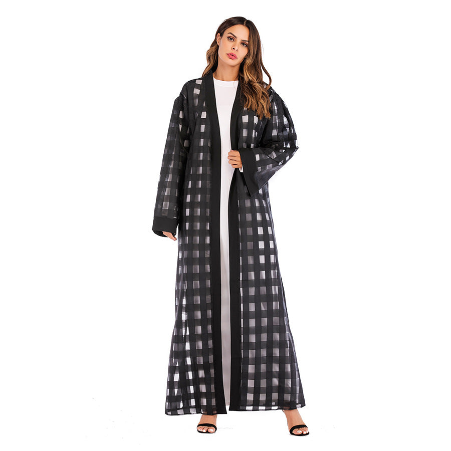Woman wearing a black and white checkered abaya on a white background