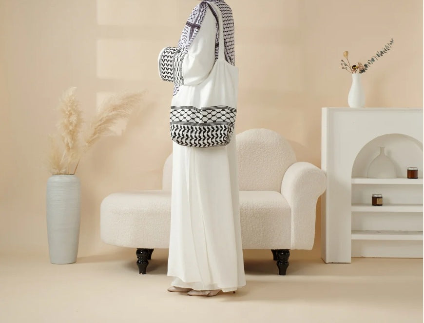 Mannequin wearing a white outfit with a patterned headscarf in a minimalistic room.