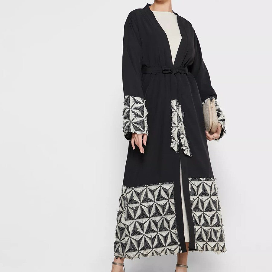 Black dress with geometric patterned sleeves and hem on a white background