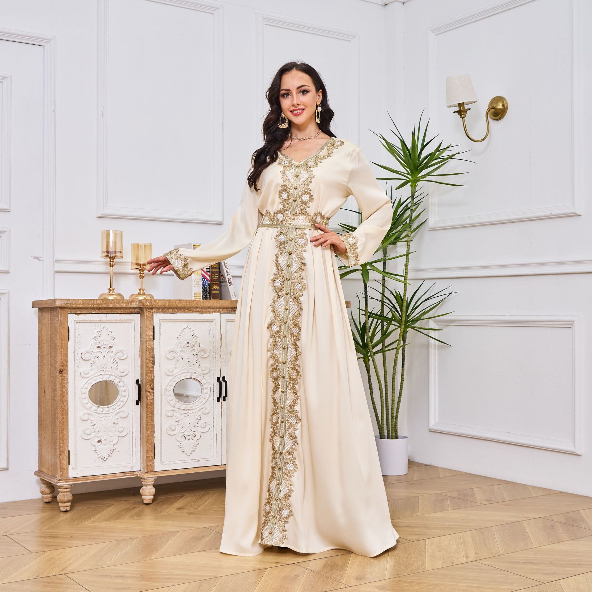 Woman in a long, elegant dress standing in a stylish room with decorative elements.
