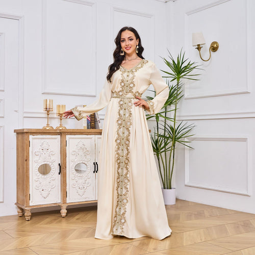 Woman in a long, elegant dress standing in a stylish room with decorative elements.