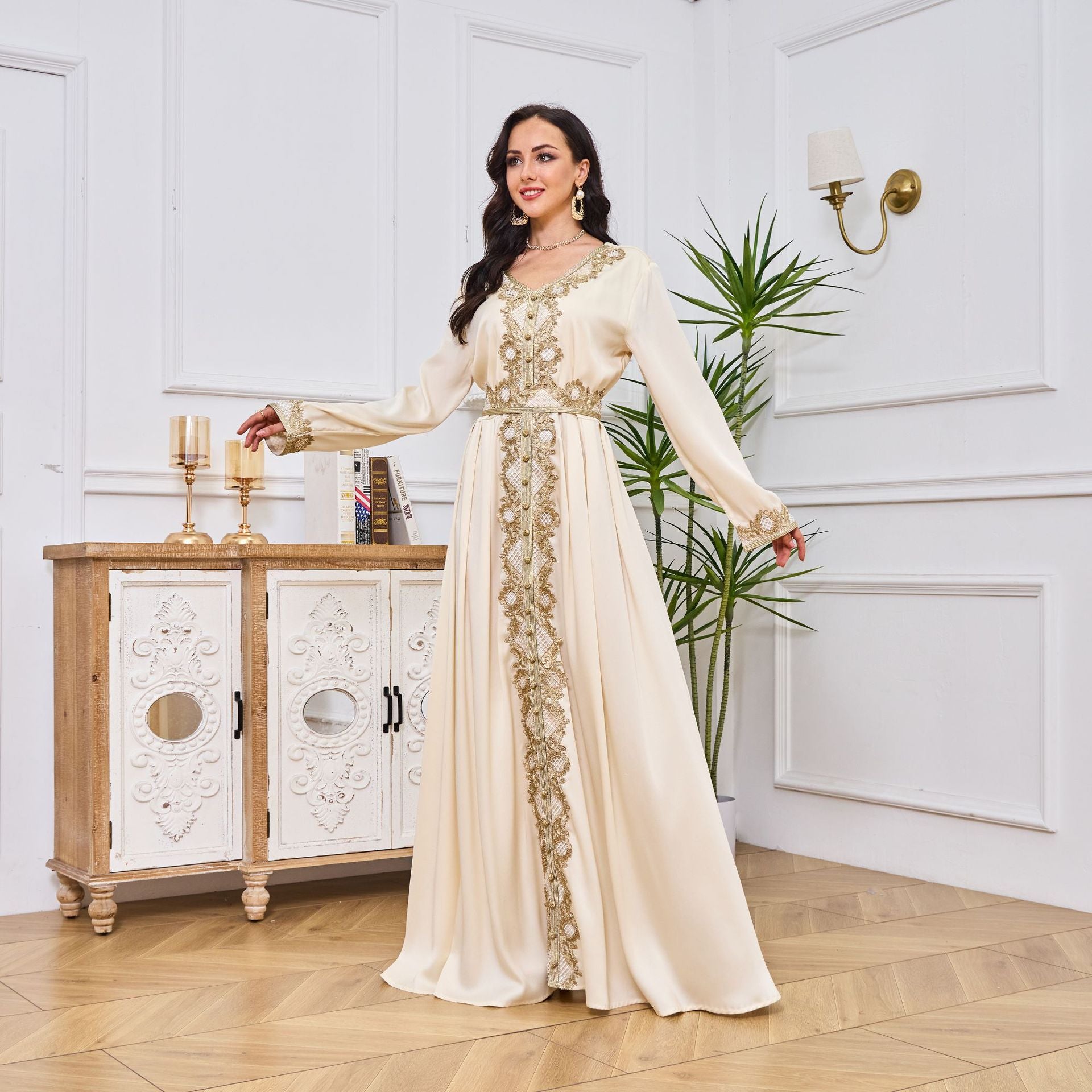 Woman in a long, elegant dress standing in a stylish room with decorative elements.