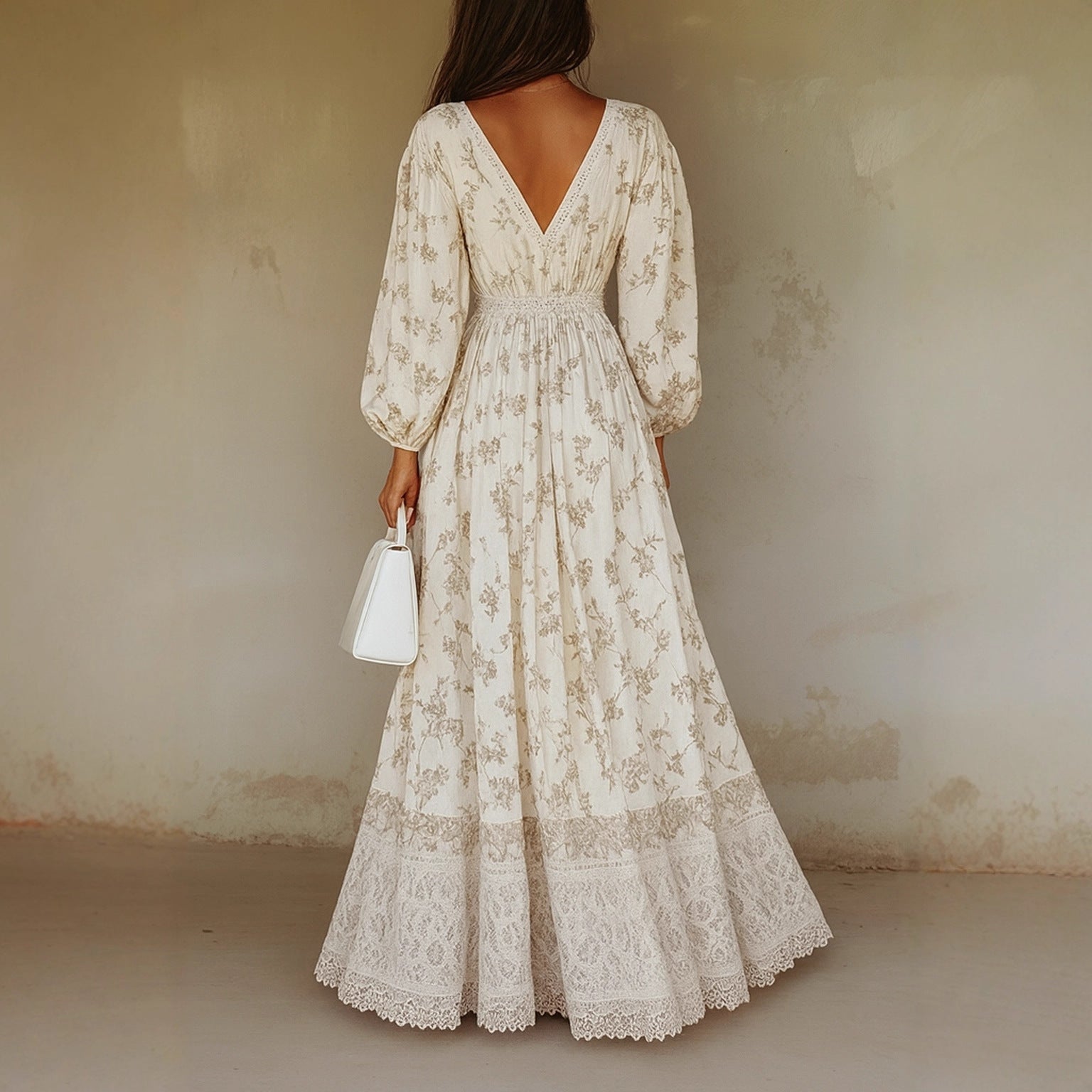 Woman wearing a long, floral lace dress against a plain wall.
