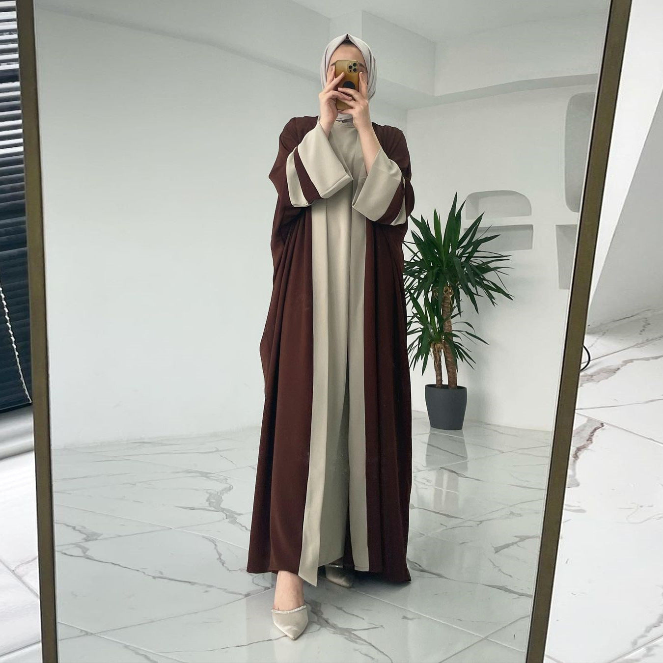 Person wearing a brown and beige abaya in front of a mirror.