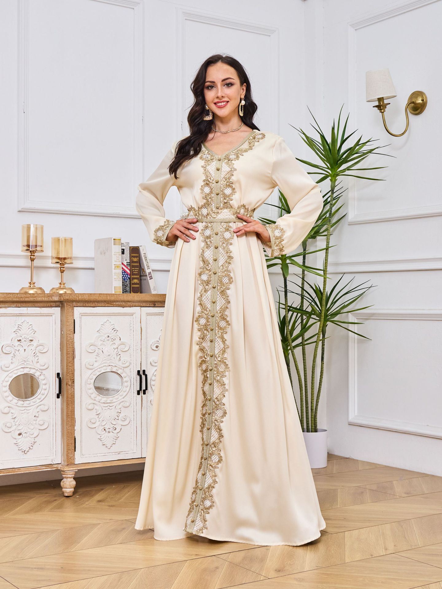 Woman in an elegant dress standing in a stylish room with decor elements.