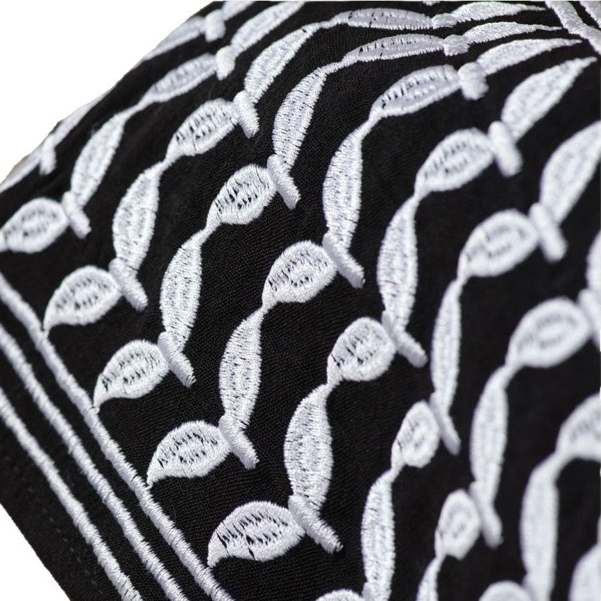 Close-up of black fabric with white embroidered leaf patterns