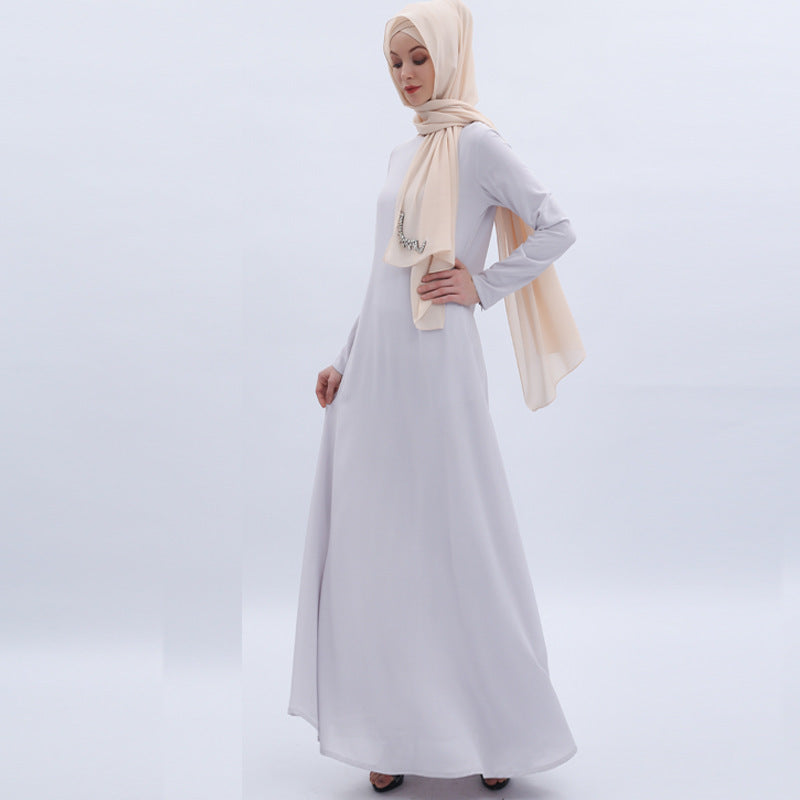 Woman wearing a white dress with a beige hijab on a light gray background