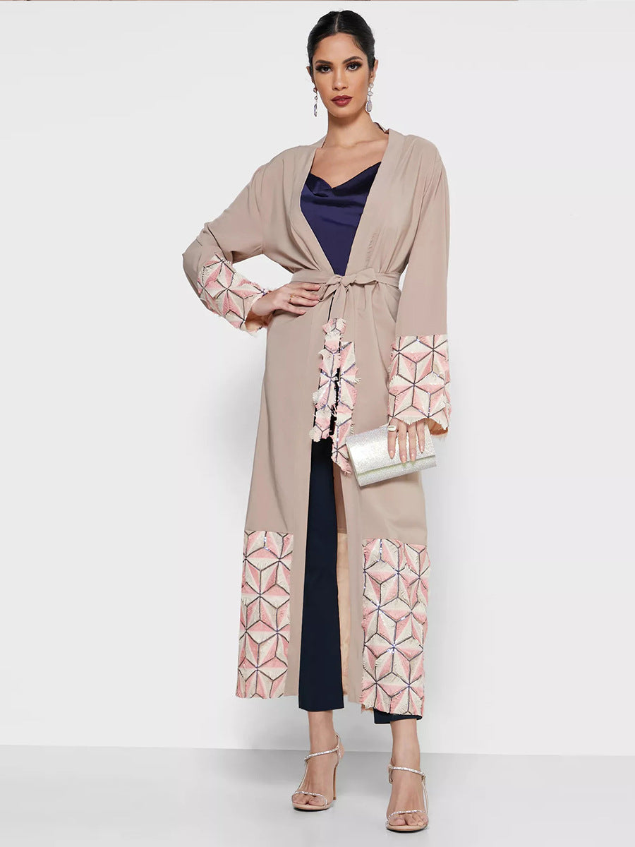 Woman wearing a beige long cardigan with geometric patterns on a white background